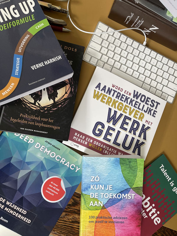 Een tafel met een stapel boeken, een toetsenbord en een muis, geschikt voor studeren of werken.