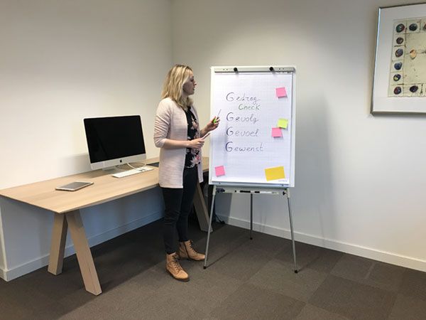 Een vrouw staat voor een whiteboard vol met kleurrijke post-its.